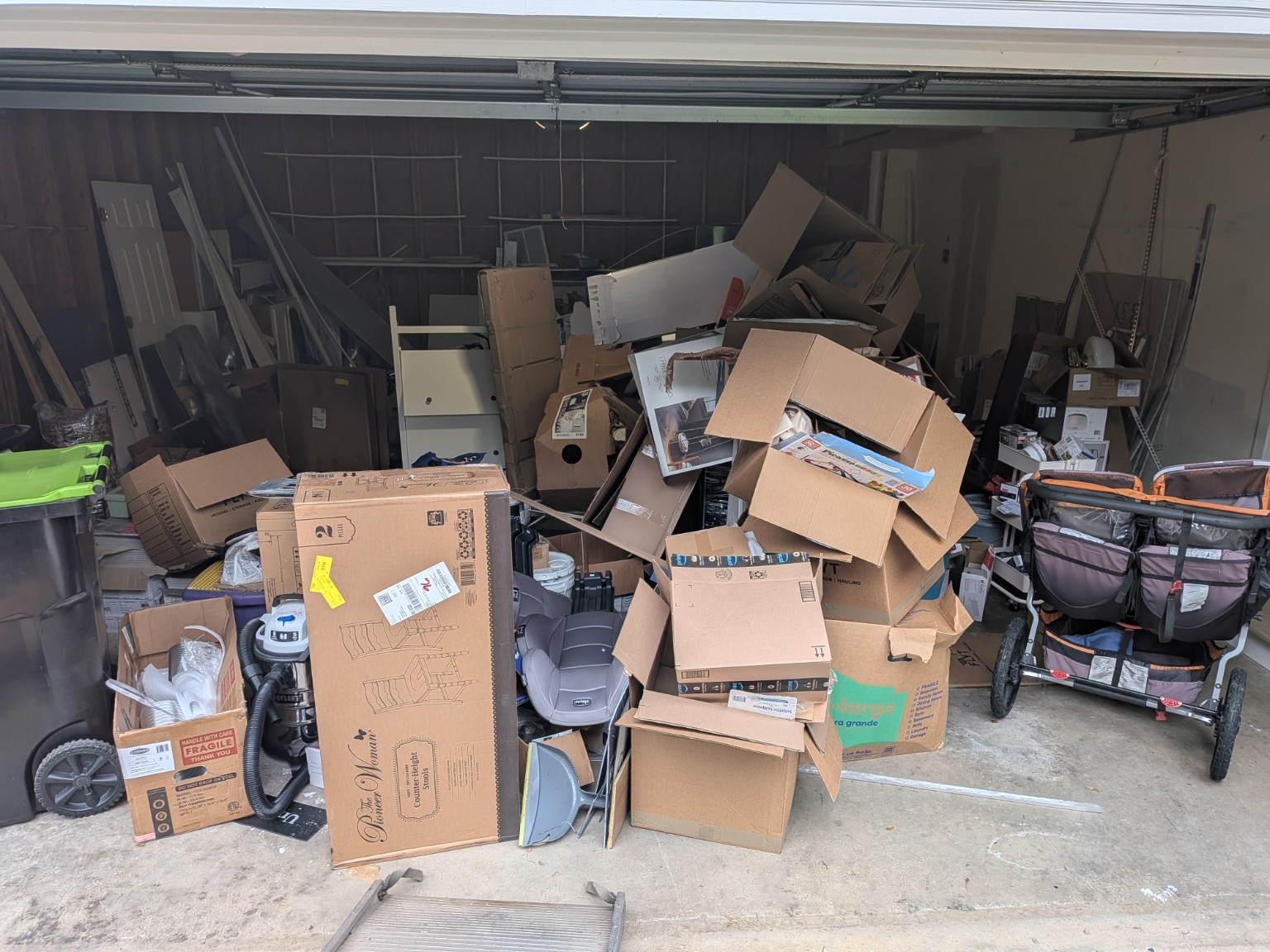 Garage before junk removal, with cardboard boxes and household clutter covering the floor