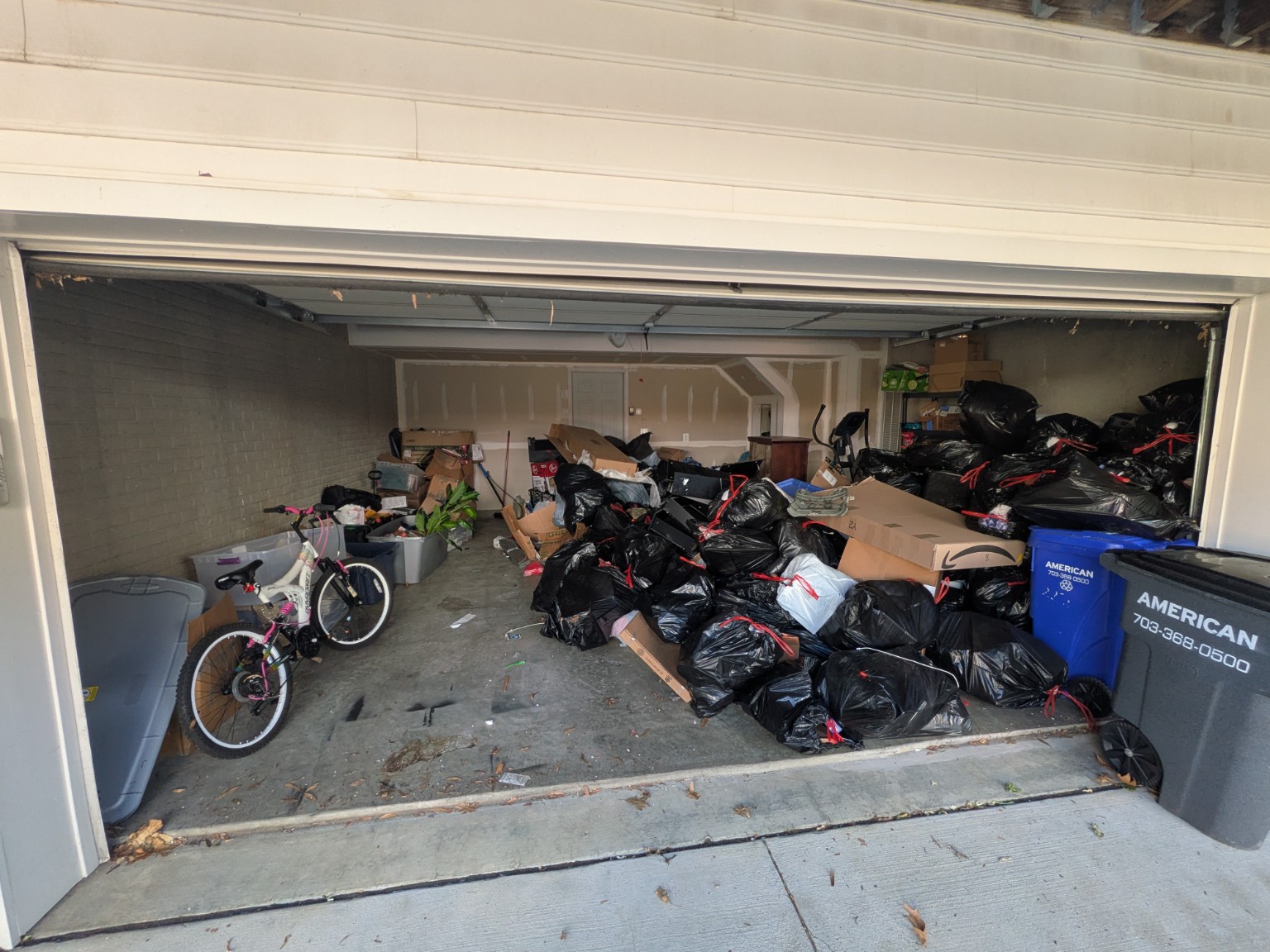 Garage before junk removal, with bagged junk and cardboard filling much of the garage